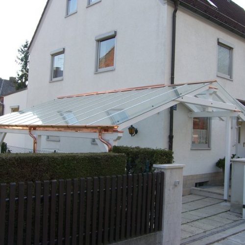 weißes Carport mit Glasdach und Kupferelementen