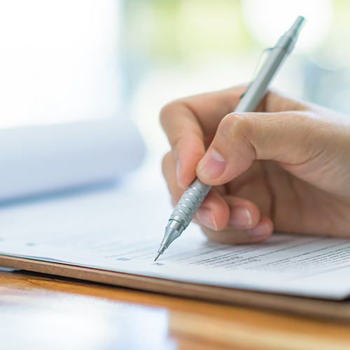 Papier und Stift in Hand als Symbol für Antrag