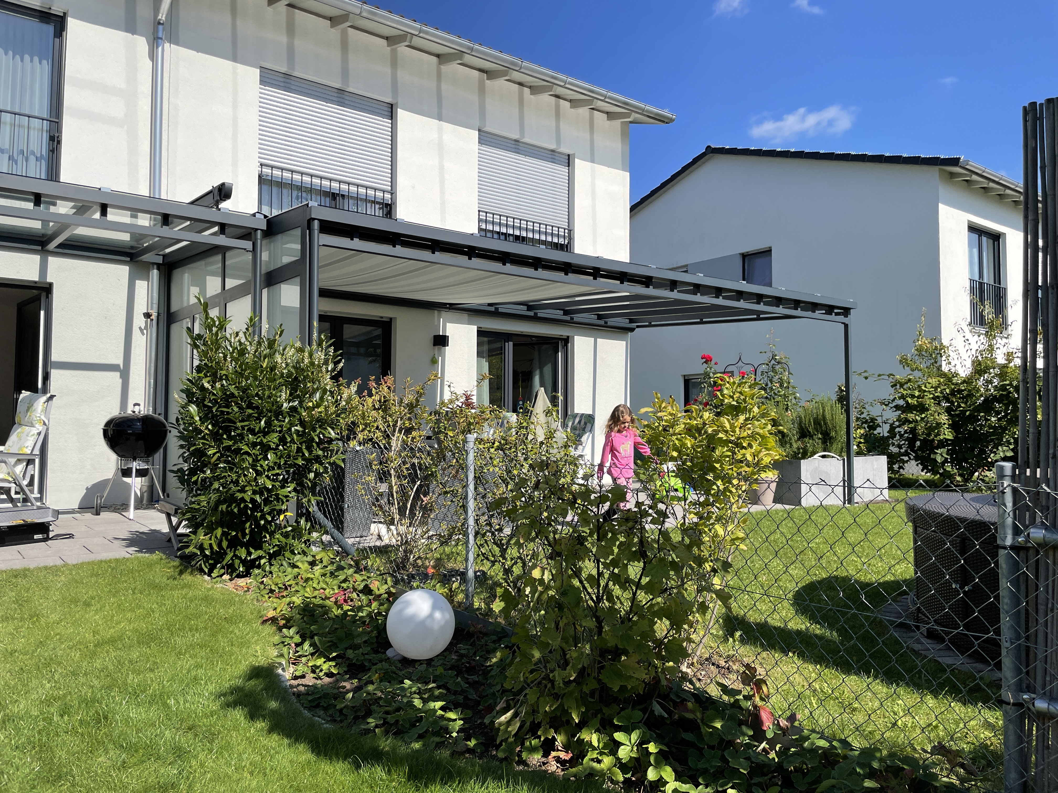 Terrassenüberdachung in München aus Aluminium mit ausgefahrener Sonnenblende