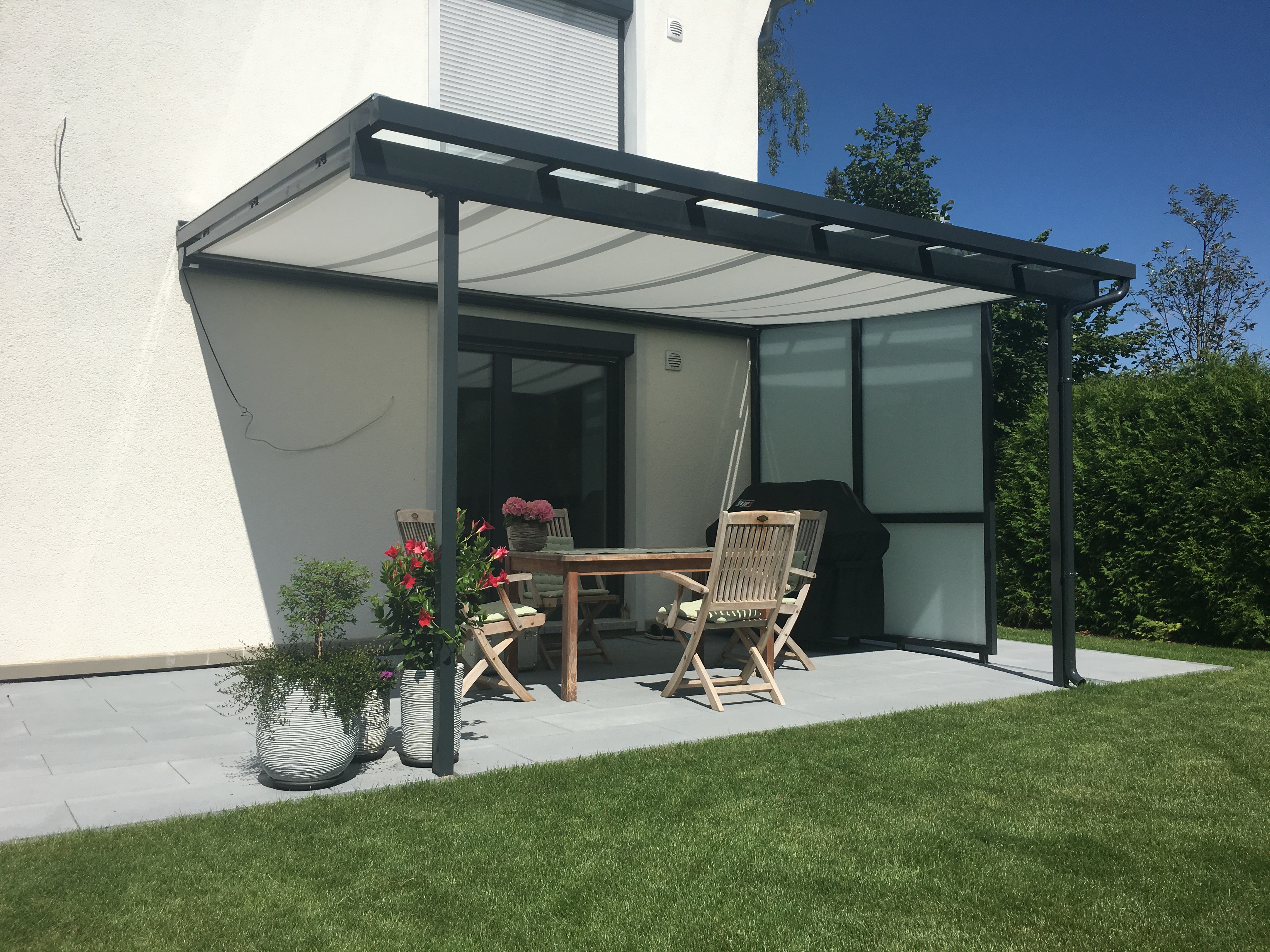 Moderne Terrassenüberdachung in München aus Aluminium und seitlichem Milchglas-Schutz