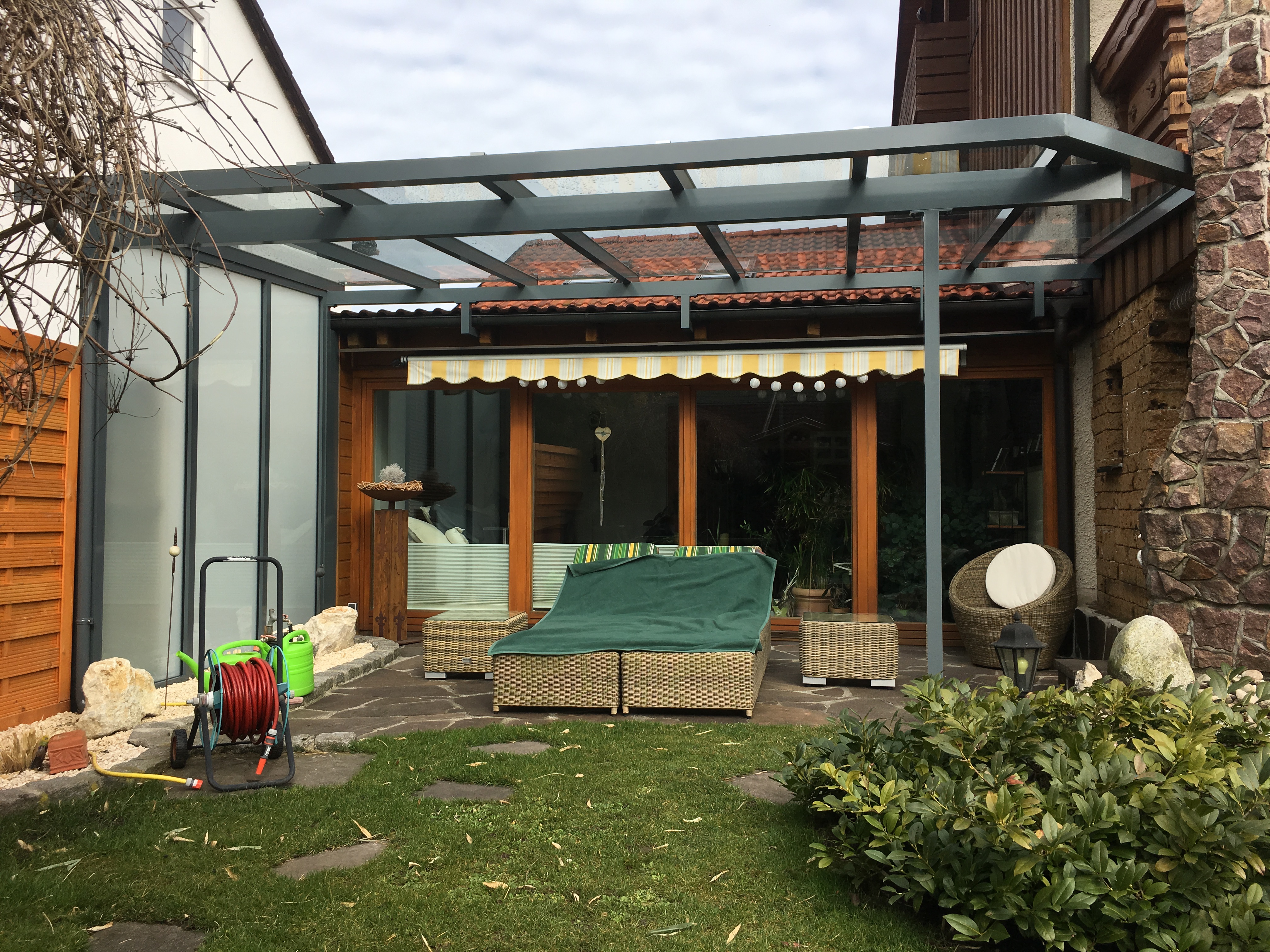 Terrassenüberdachung in München aus Aluminium und Glas mit seitlichem Milchglas-Schutz